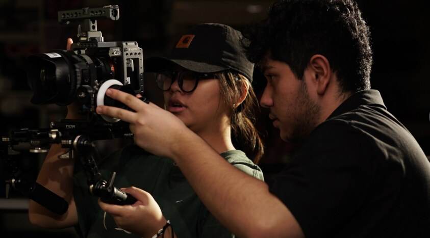 Camera assistant pulling focus on a rigged cinema camera