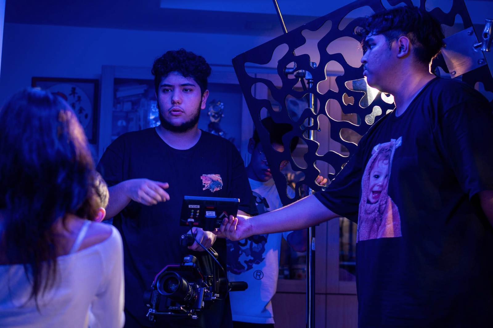 Crew discussing a shot around a gimbal rig and monitor under blue set light