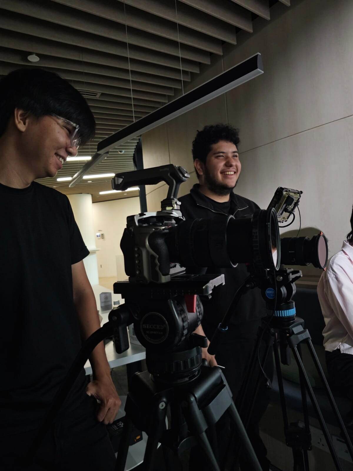 Two crew members setting up cameras on tripods for an interview